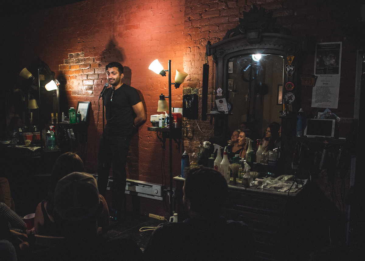 Stand up comedian onstage inside Original Barbershop in the East Village